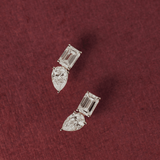 14k gold diamond earrings emerald and pear shaped set in prongs showcased in the ear of a model. 