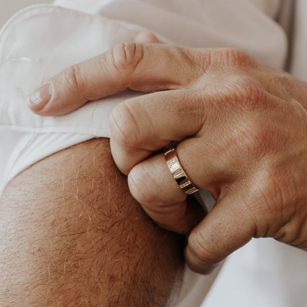 Close-up of a person wearing a gold ring on a blurred background