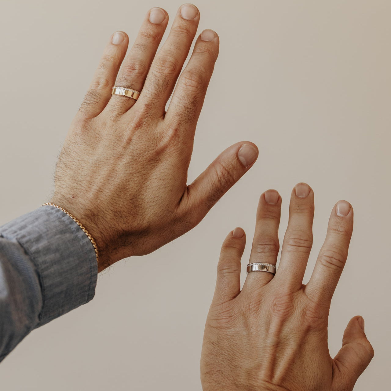 Two hands with wedding rings on a beige background