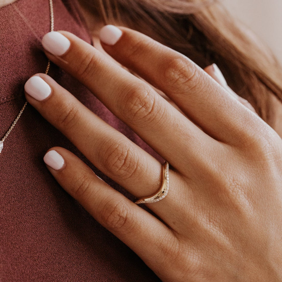 Close-up of a hand wearing a gold wedding with pave diamonds with a blurred background