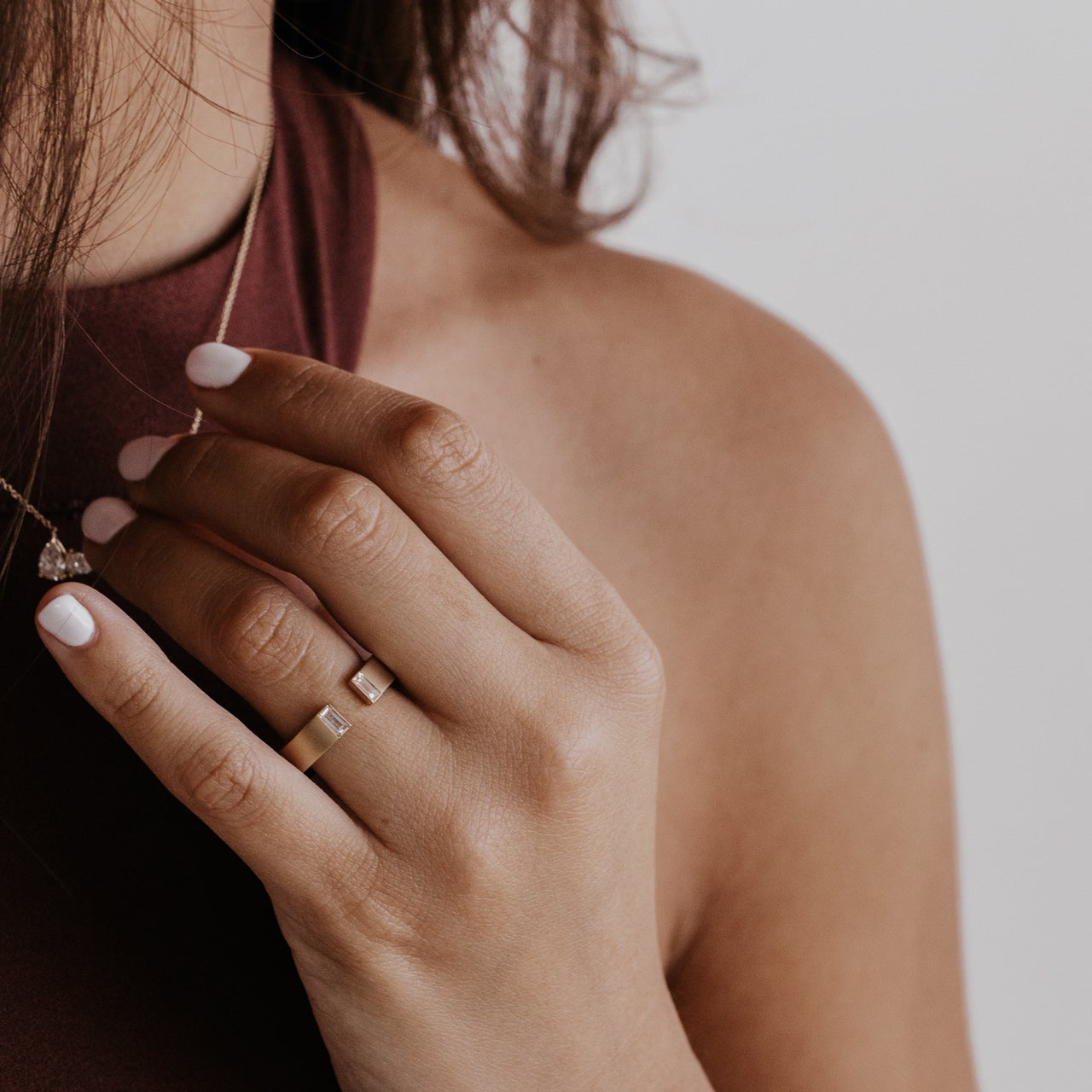 Close-up of a person wearing a gold band with baguette diamonds with a blurred background