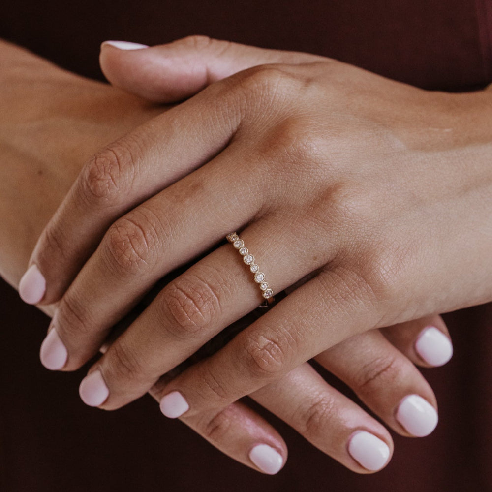 Close-up of hands with a gold diamond wedding band on a dark background
