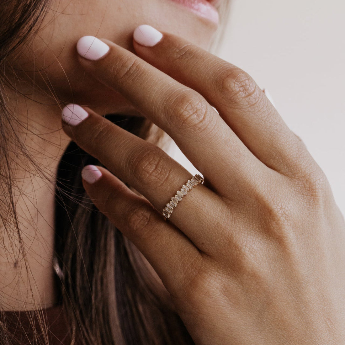 Close-up of a hand with a gold diamond wedding band on a blurred background