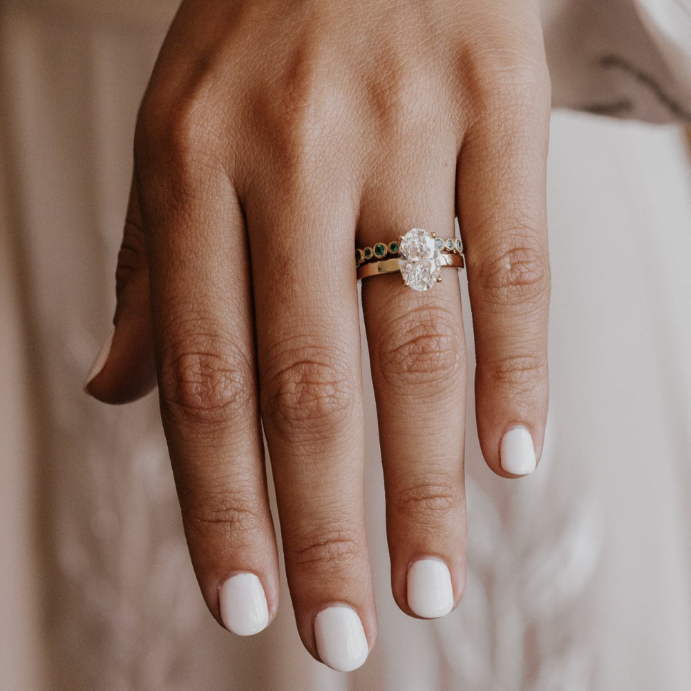 Hand wearing a diamond oval engagement  ring with a blurred background