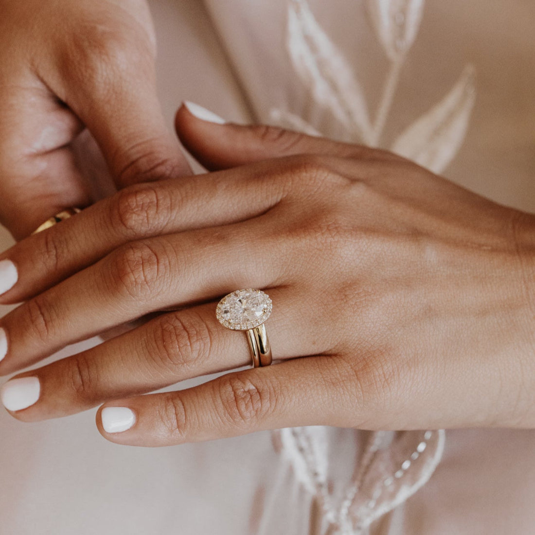 Close-up of a hand wearing a diamond ring with a gold wedding band soft background