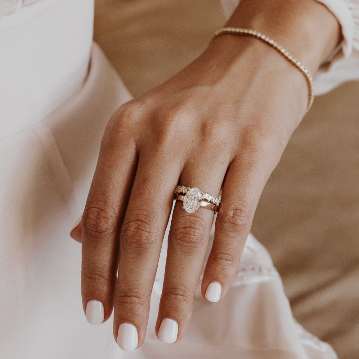 Close-up of a hand wearing a wedding band with a oval diamond engagement ring with a blurred background