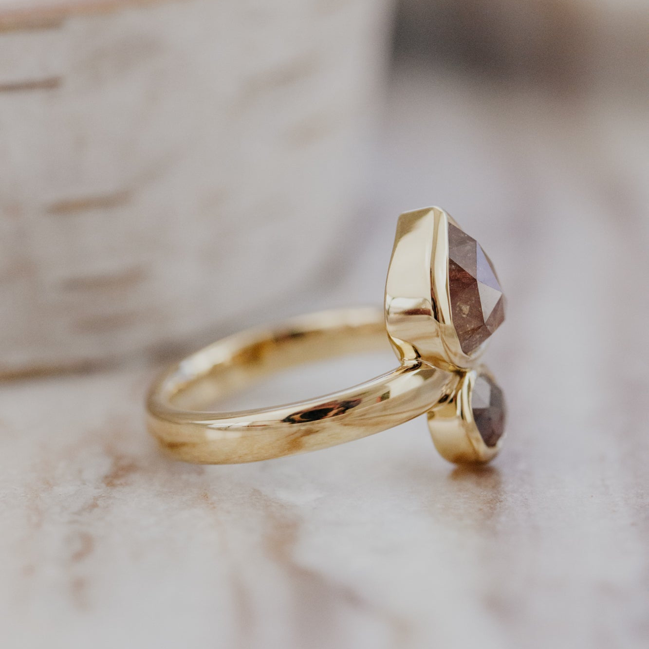 Gold Reese ring with rustic diamonds on a marble surface.