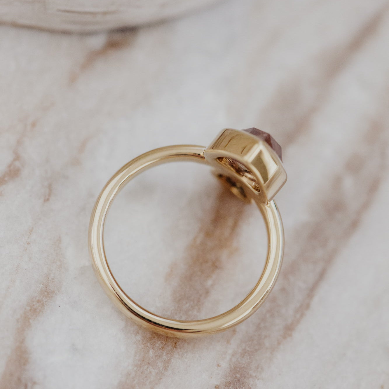 Gold Reese ring with a rustic diamonds on a marble surface.