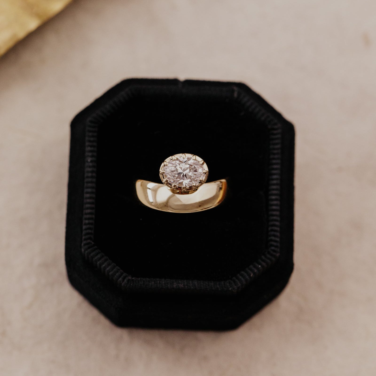 Gold Reflection pinky ring with an oval lab grown diamond in a black velvet cushion ring box.
