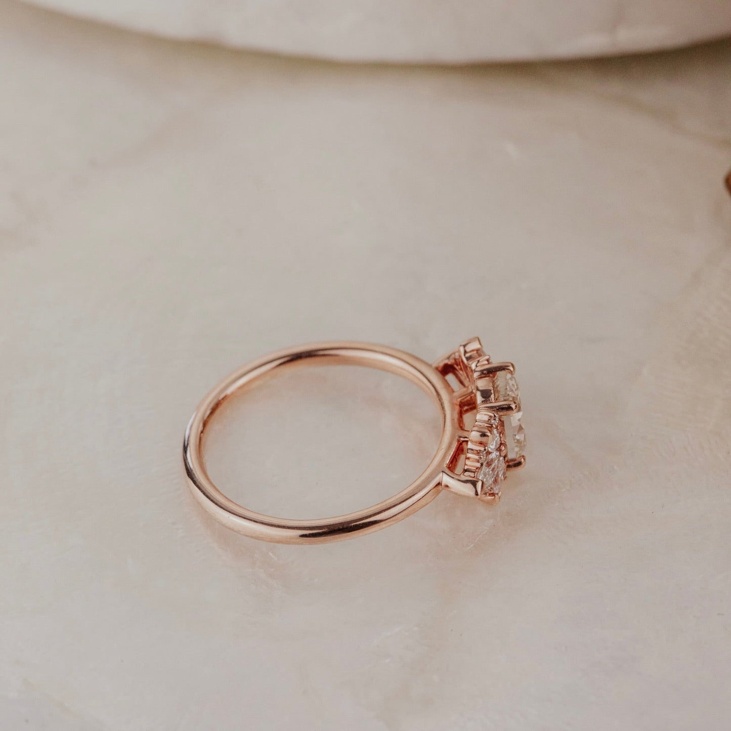 Rose gold ring with a champagne diamond on a beige surface.