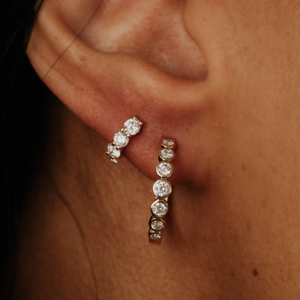 Close-up of diamond hoop earrings on an ear.
