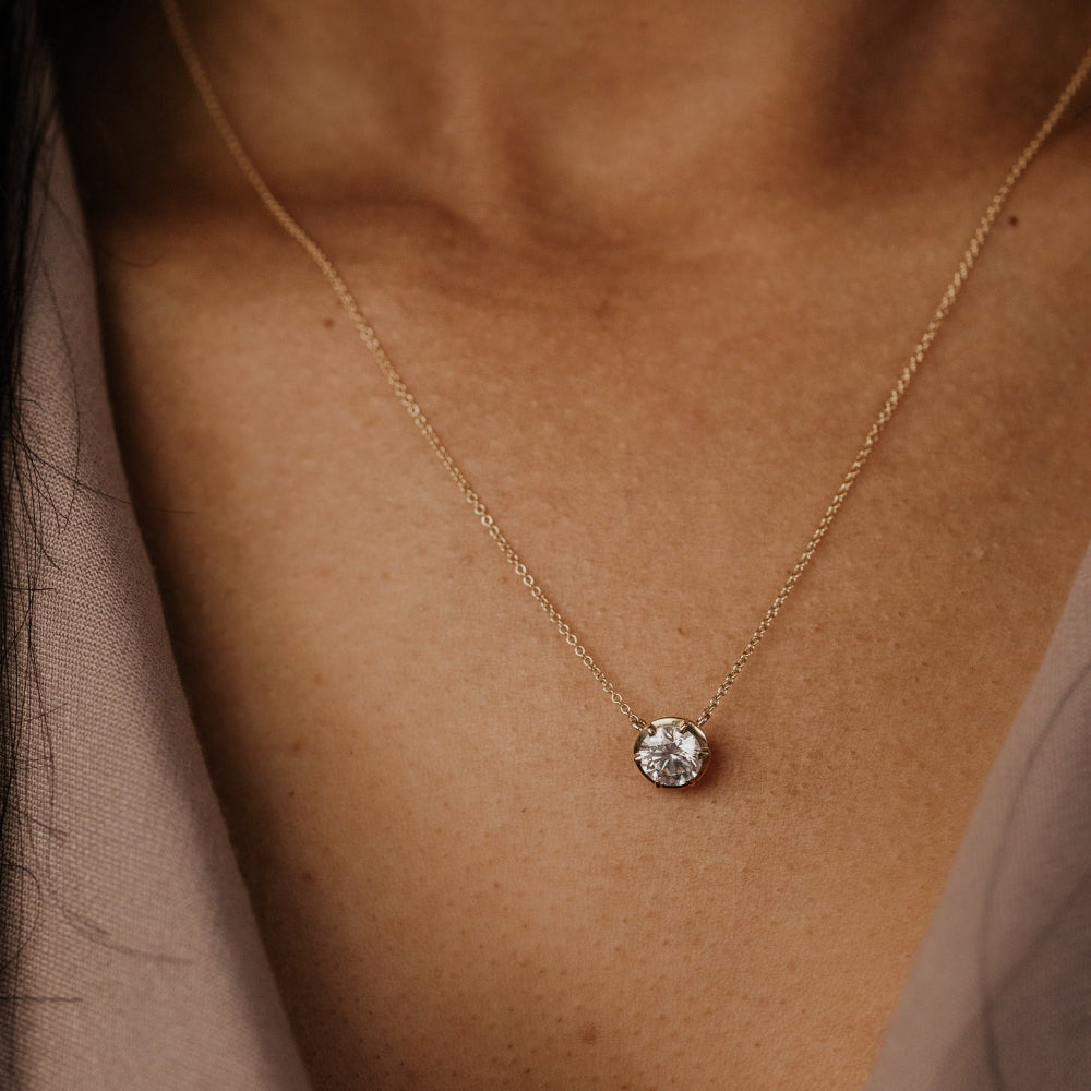 Necklace with a round lab grown diamond pendant on a person's neck.