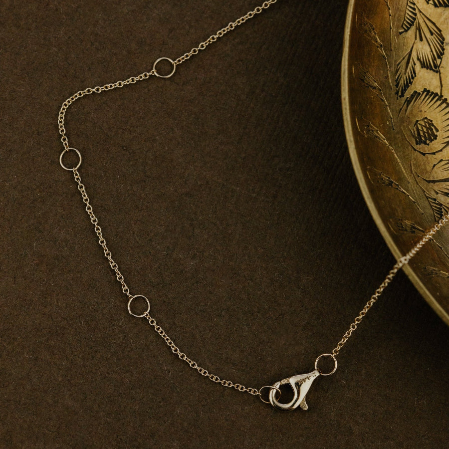 Yellow chain necklace with a pendant on a textured brown surface.