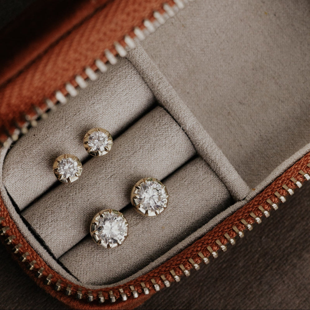 Diamond earrings in a jewelry case with brown leather trim.