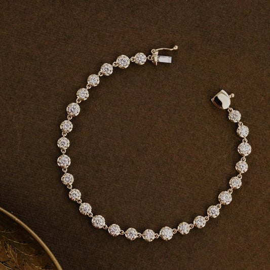 Yellow gold tennis bracelet with round lab grown diamonds on a brown surface.