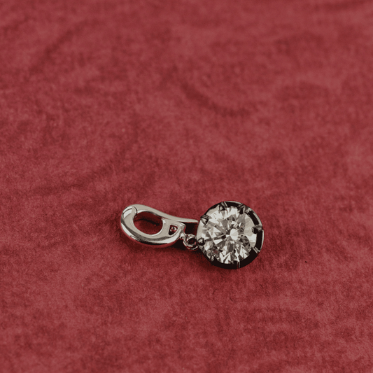 14k gold round-cut diamond with Black Rhodium clip pendant featured on a textured red surface.  