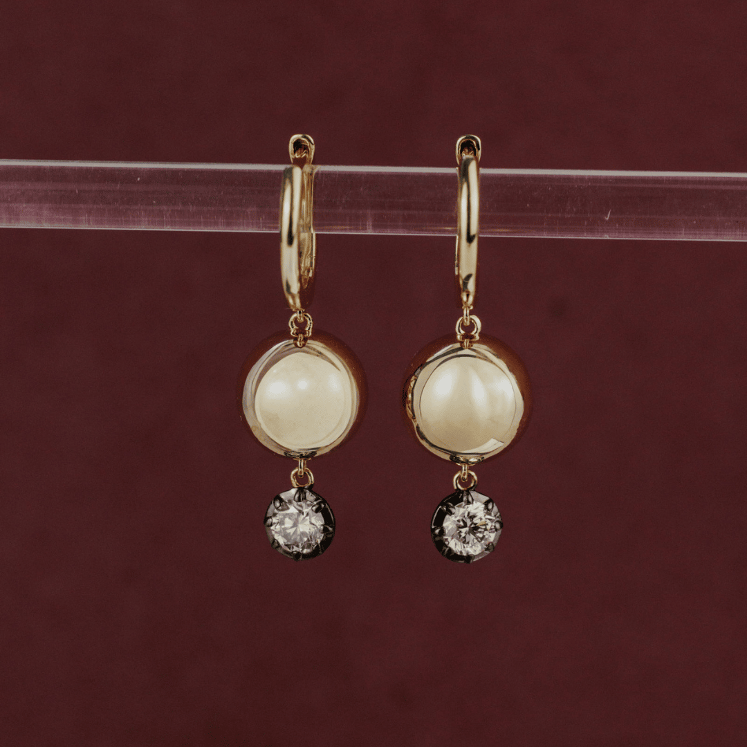 14k gold round cut, lab grown diamond dangle/hoop earrings with Black Rhodium featured on a clear tube in the center of the frame. 
