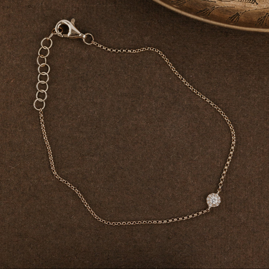 Gold bracelet with a diamond on a brown textured surface.