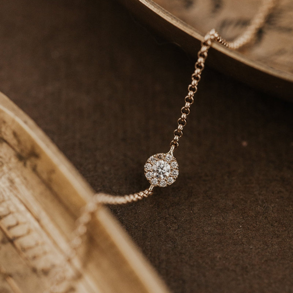 Delicate gold chain bracelet with a diamond on an old book.
