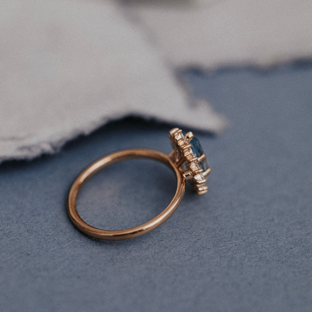 Gold ring with a blue gemstone on a textured surface
