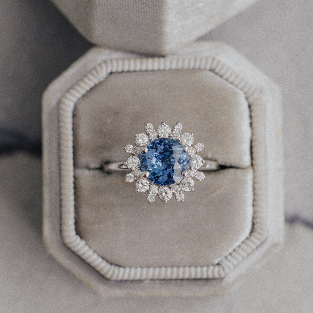 Diamond ring with a blue gemstone in an octagonal box on a textured surface