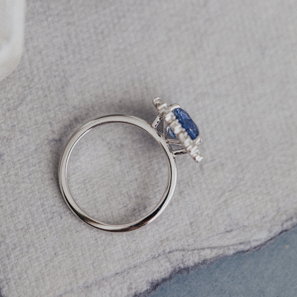 White gold ring with a blue gemstone on a textured gray surface