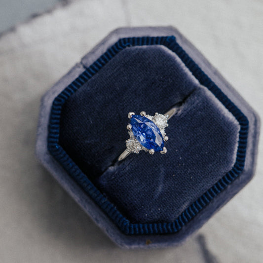 Ring with a blue sapphire in a blue velvet box on a textured surface