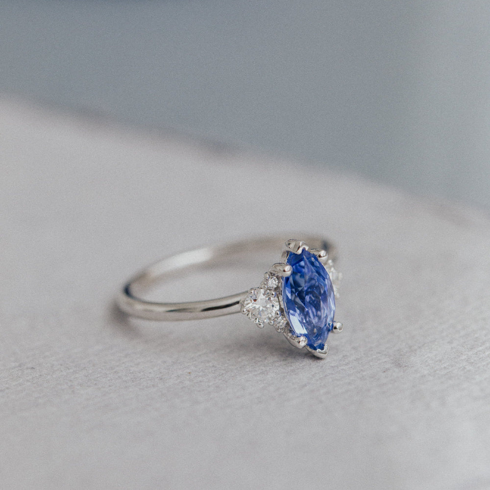Ring with a blue sapphire on a light gray surface