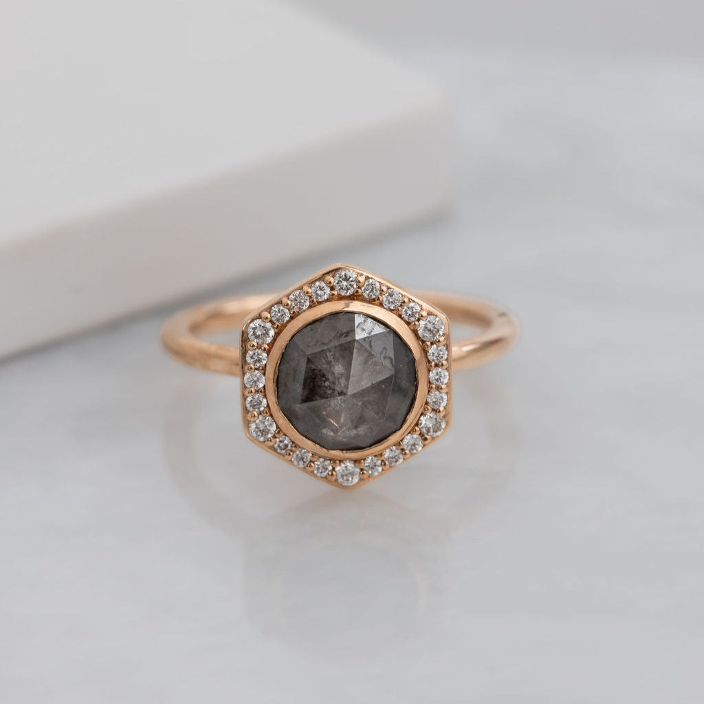 A 14k rose gold ring featuring a round galaxy diamond center stone with a hexagon diamond halo