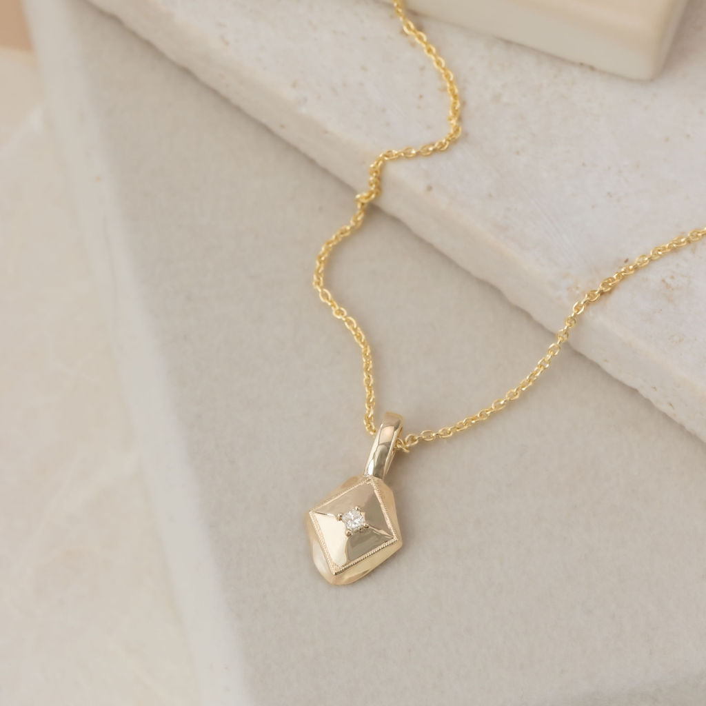 Gold necklace with a pendant on a soft beige background
