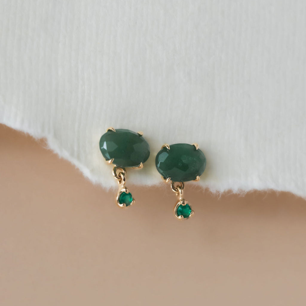 A pair of gold earrings featuring oval aventurine stones with green onyx dangles, displayed against a neutral background.