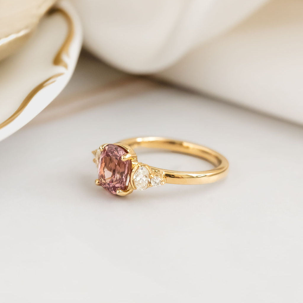 Gold ring with a pink garnet on a beige fabric background
