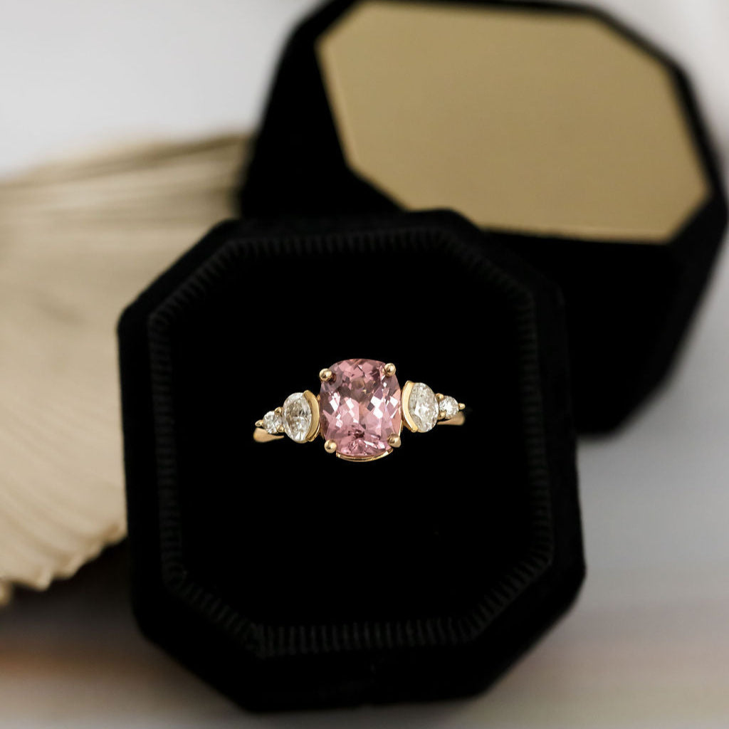 Pink garnet ring in a black velvet box on a light background