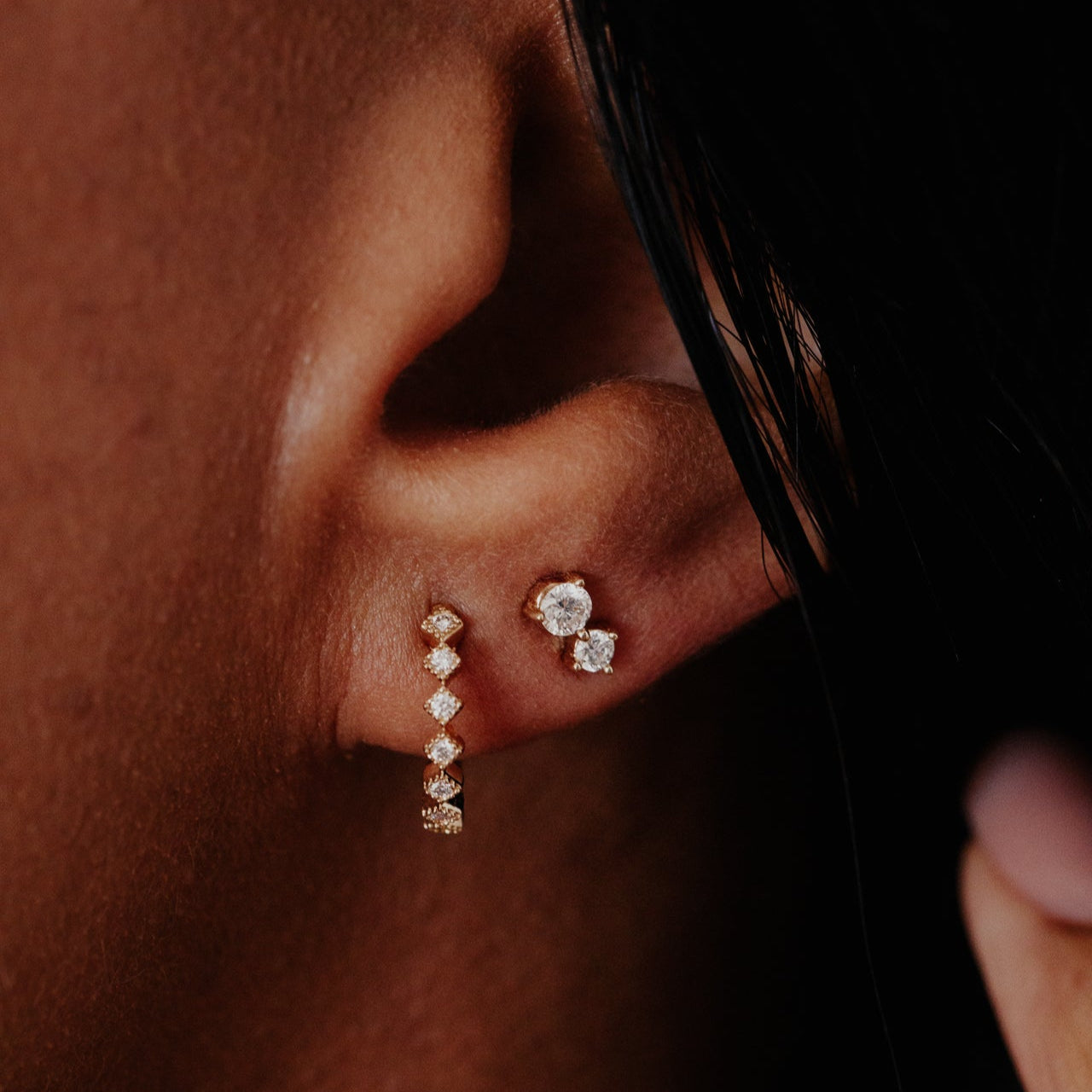 Close-up of an ear wearing diamond earrings with a blurred background