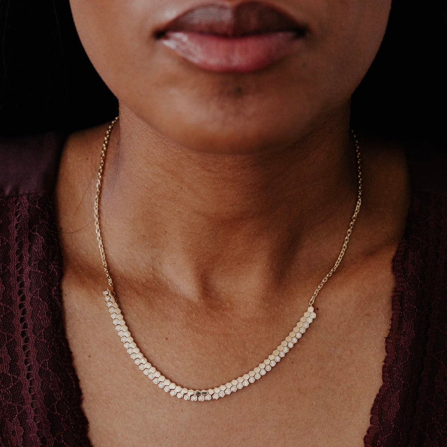 Close-up of a person wearing a gold necklace with a dark background