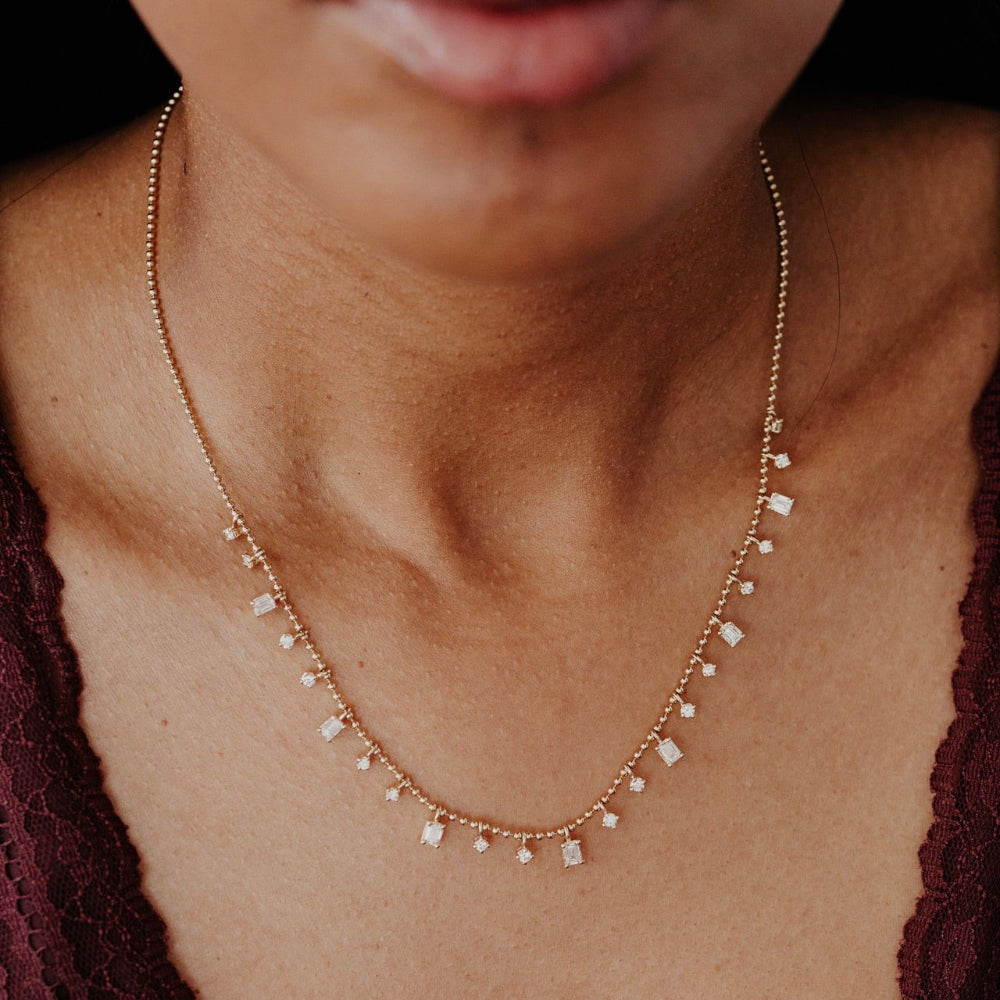 Necklace with small diamond pendants on a person wearing a dark top.