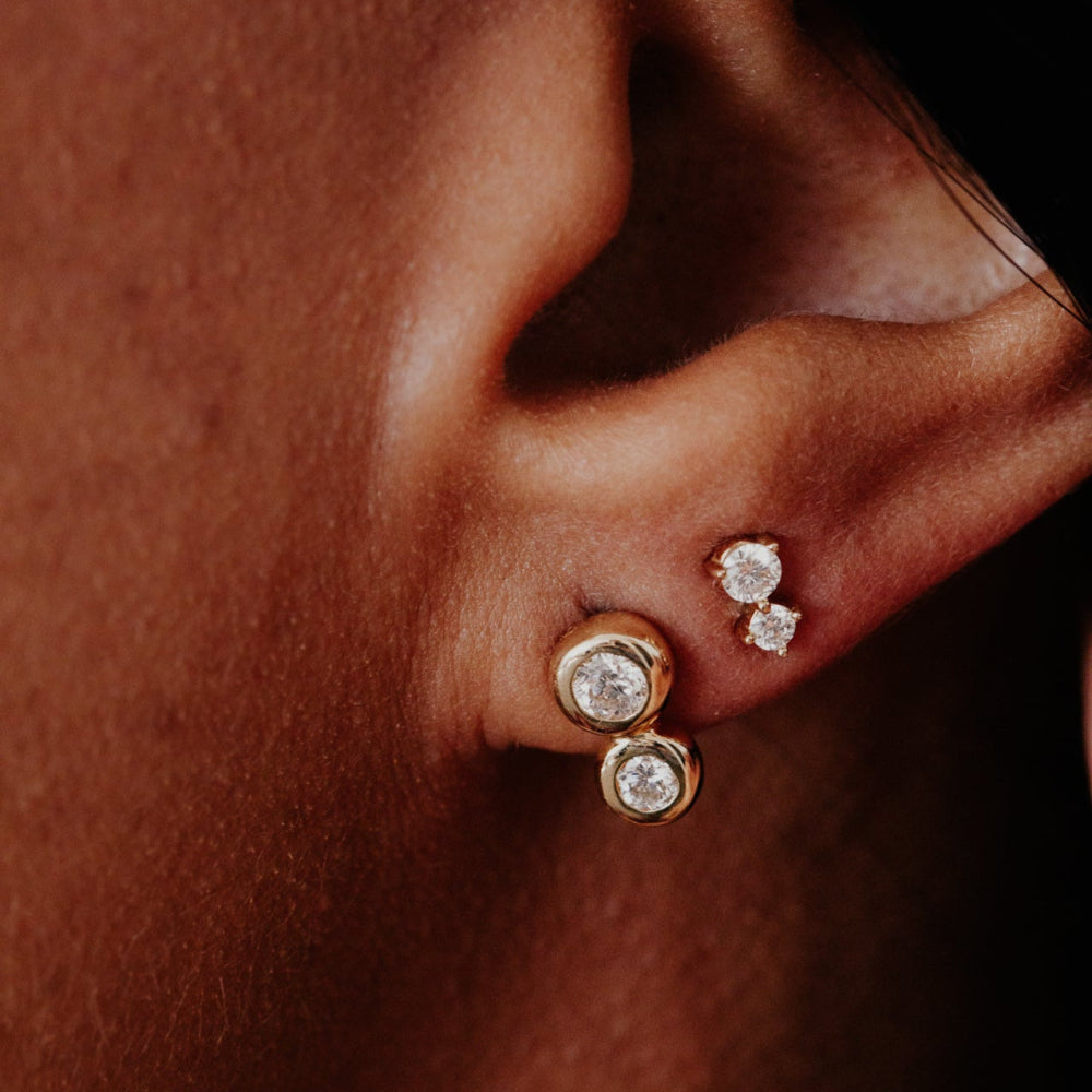 Close-up of an ear wearing gold earrings with diamonds.