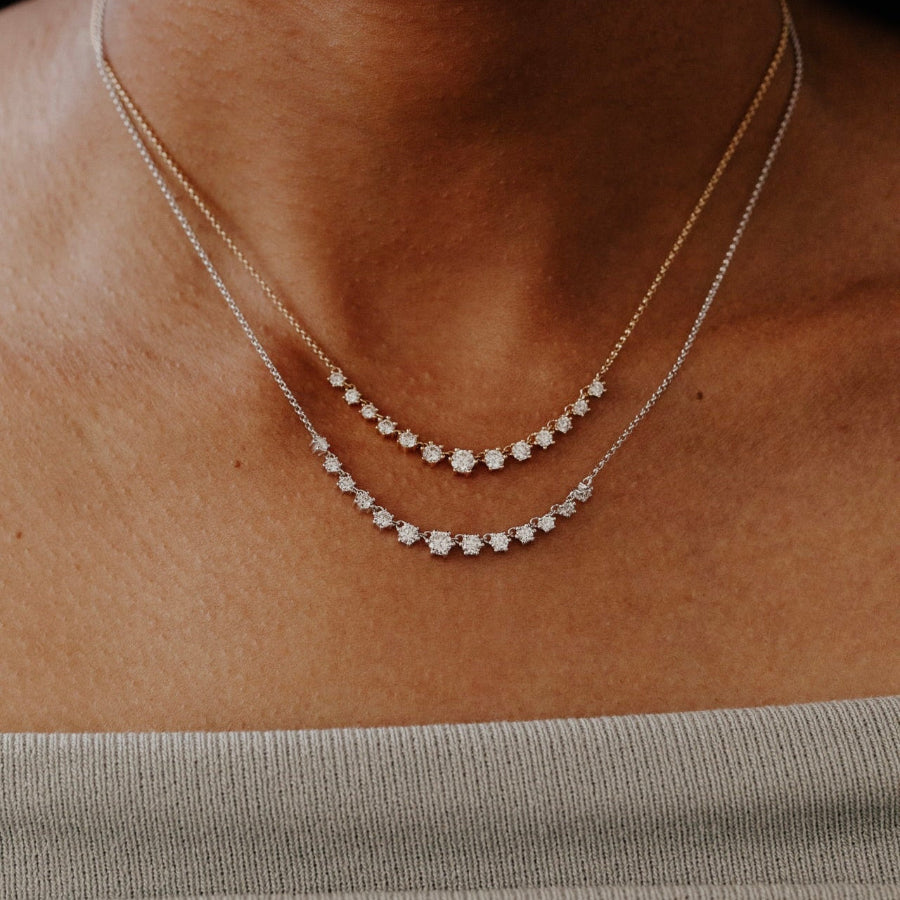 Close-up of a person wearing a delicate gold necklace with small diamonds.