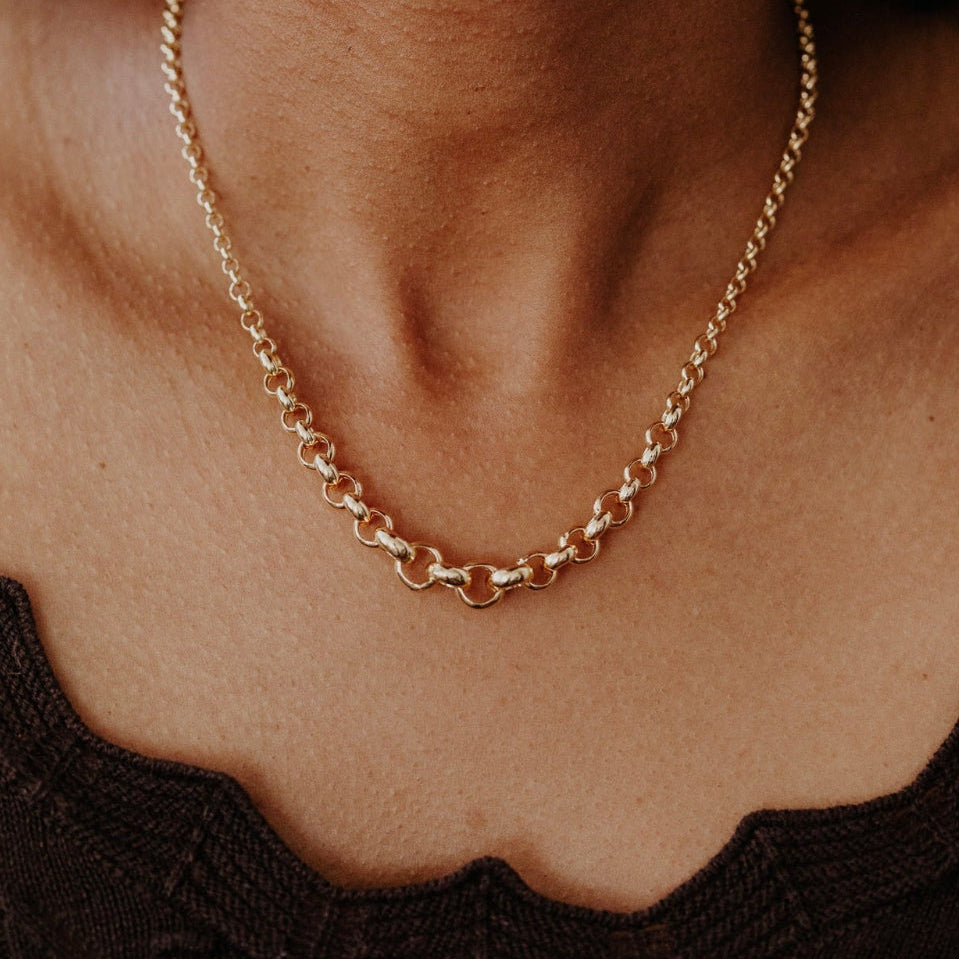 Gold chain necklace on a person's neck with a blurred background