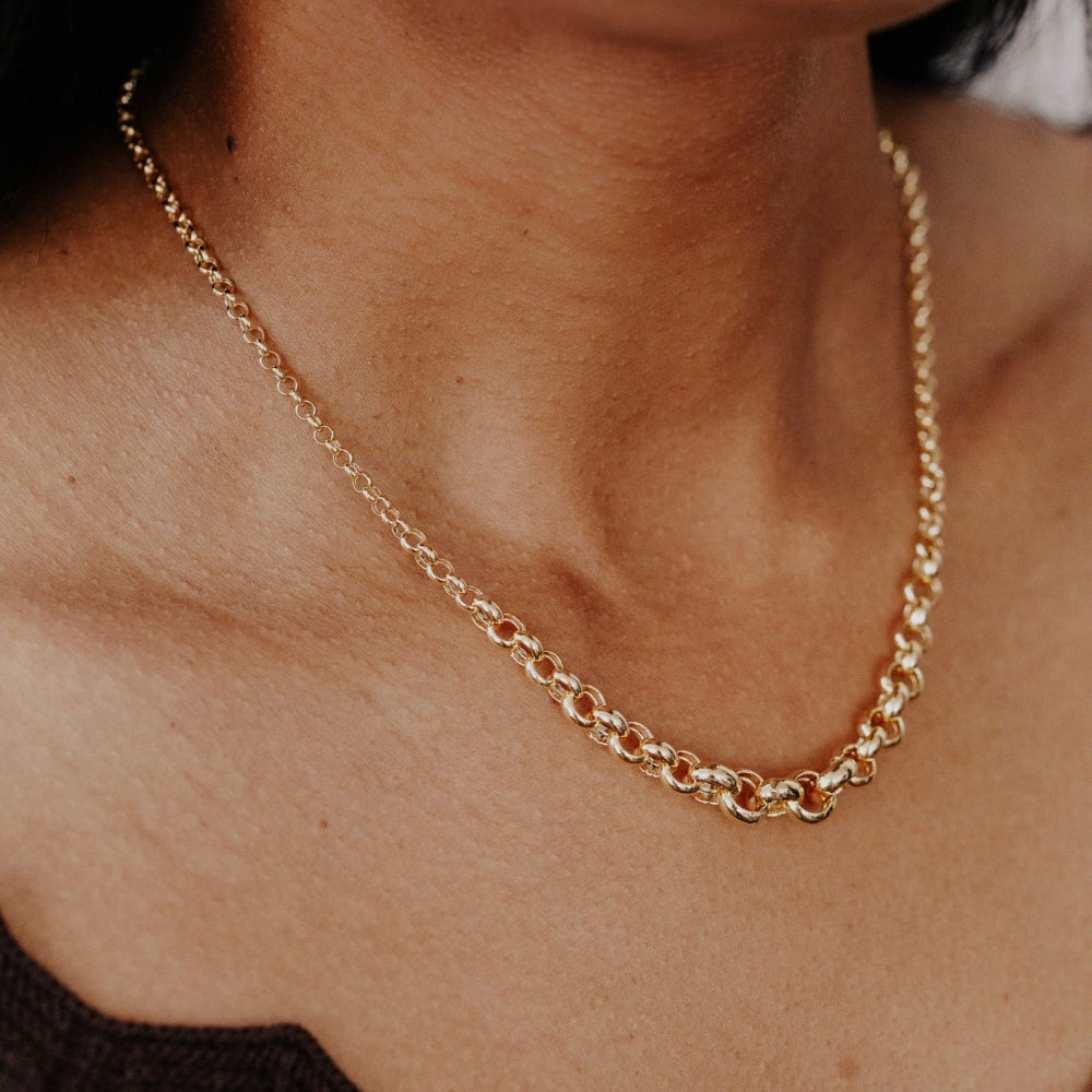 Gold chain necklace on a person's neck with a blurred background