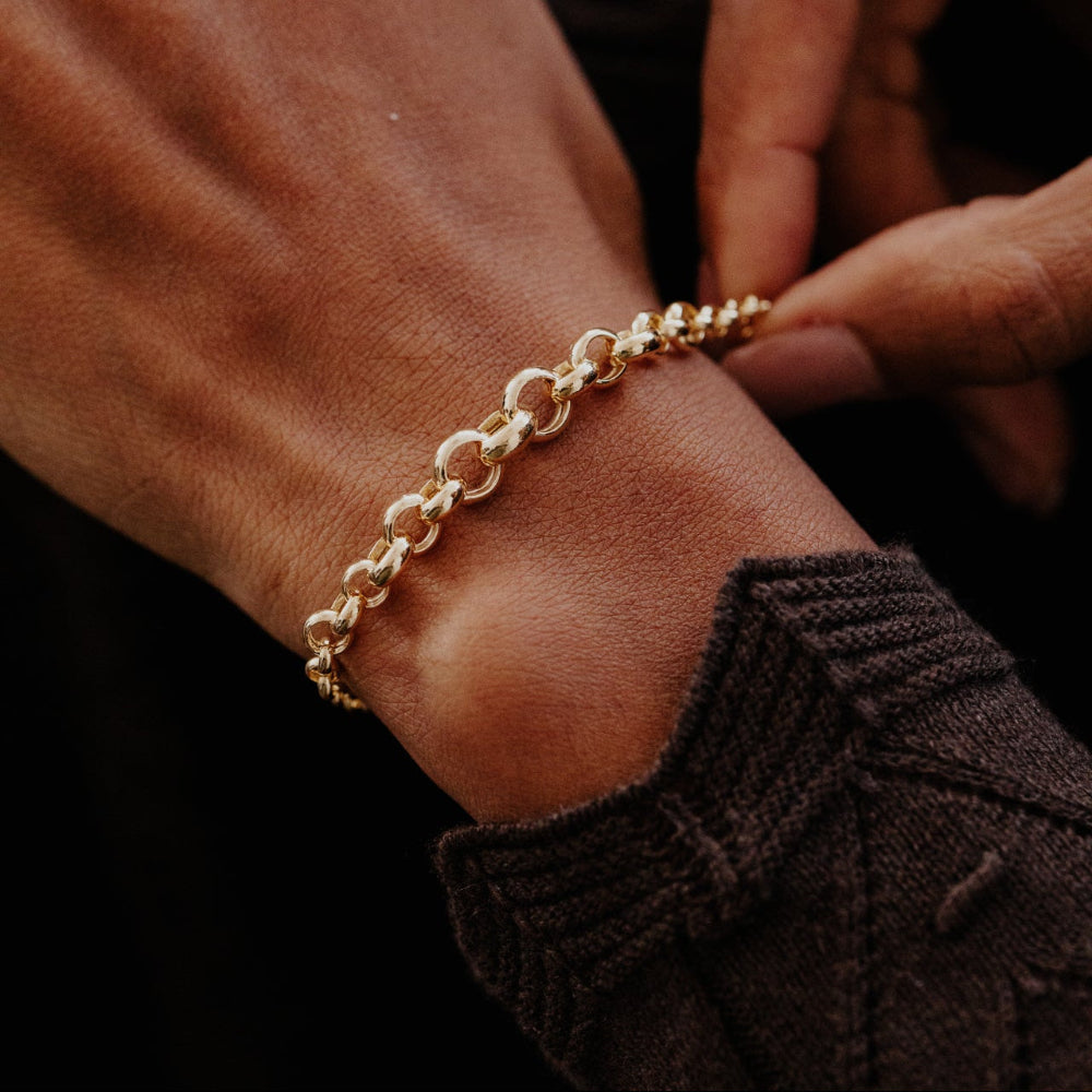 Gold bracelet on a wrist with a dark background
