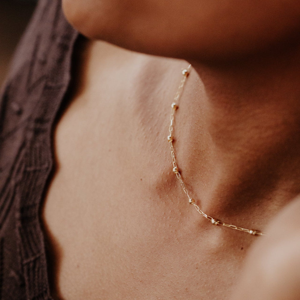 Gold necklace on a person's neck with a blurred background