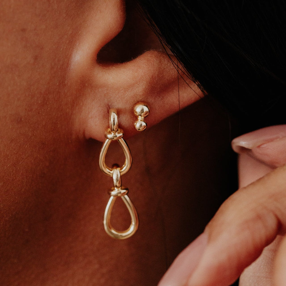 Close-up of an ear wearing gold earrings with a blurred background