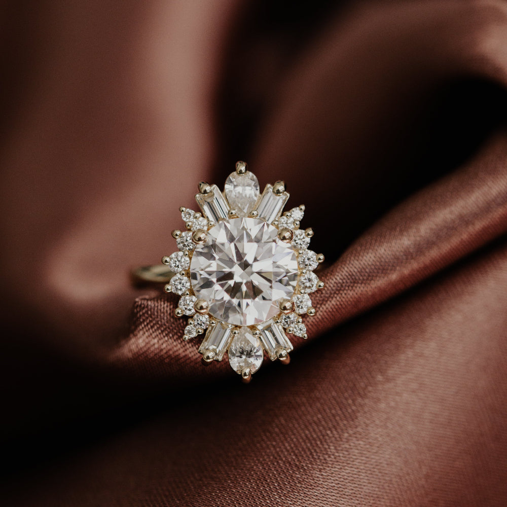 Round diamond halo engagement ring on a silk brown surface