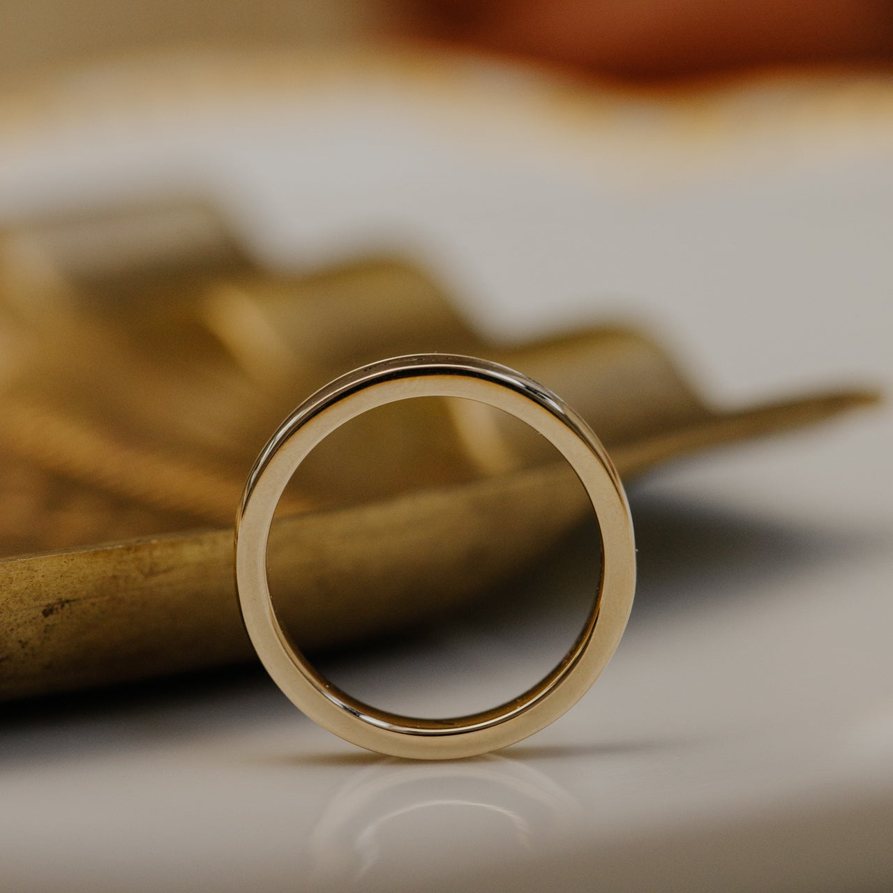 Gold wedding band on a textured surface with blurred background