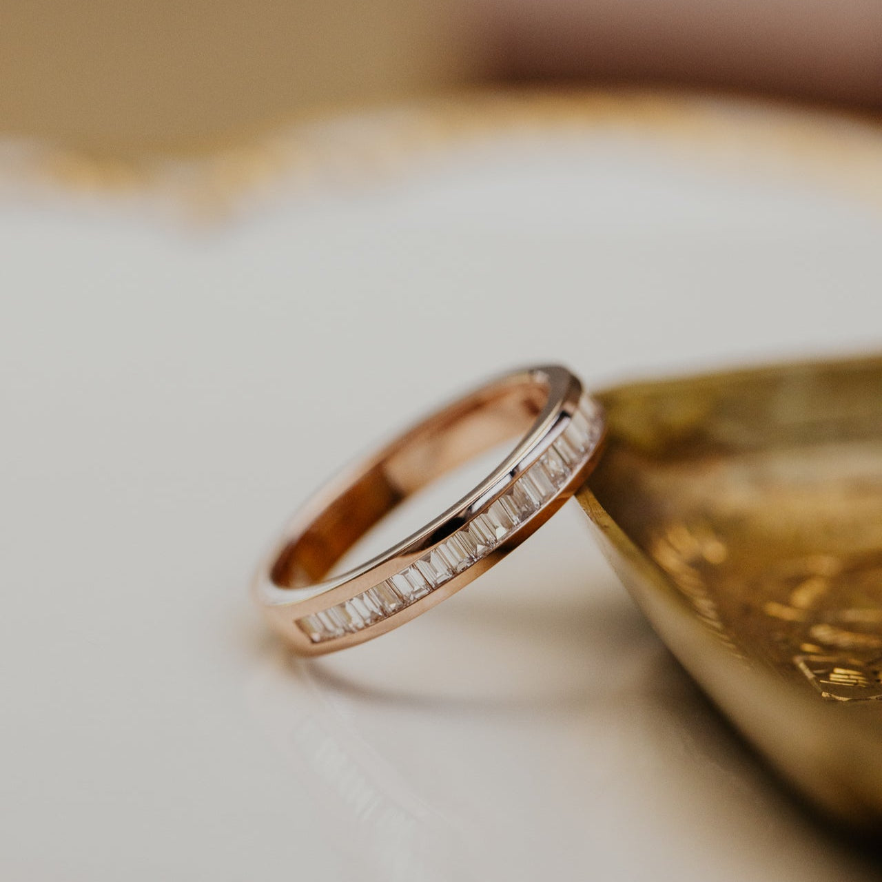 Rose gold wedding band with diamond accents on a textured surface