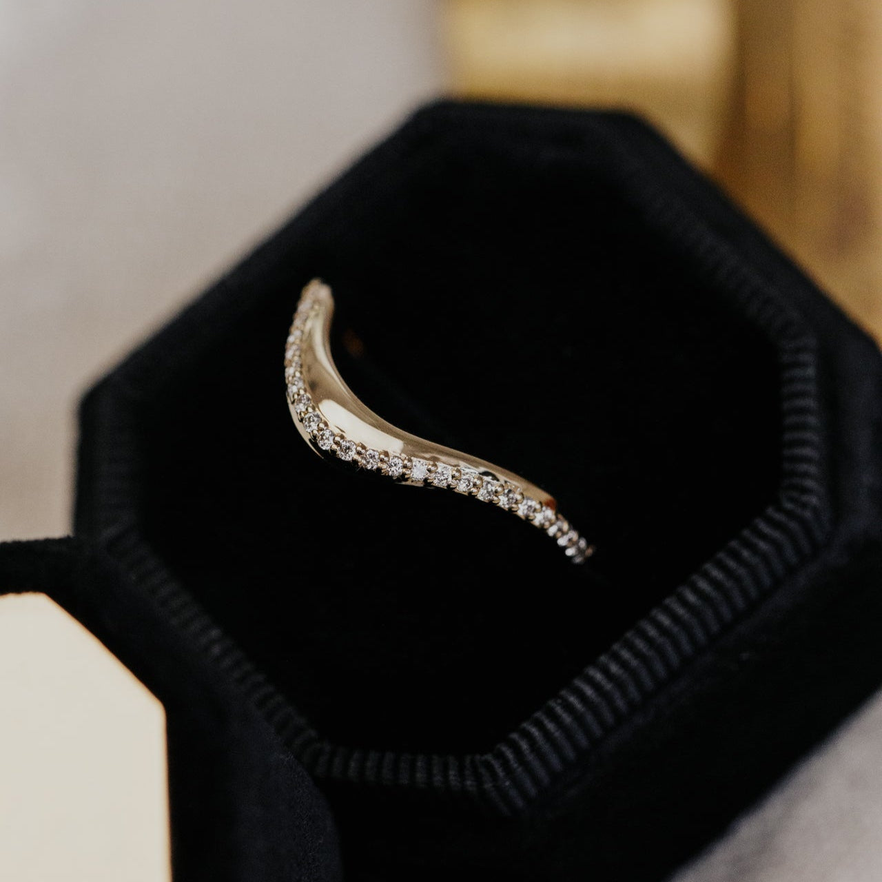 Diamond wedding band on a black hexagonal stand