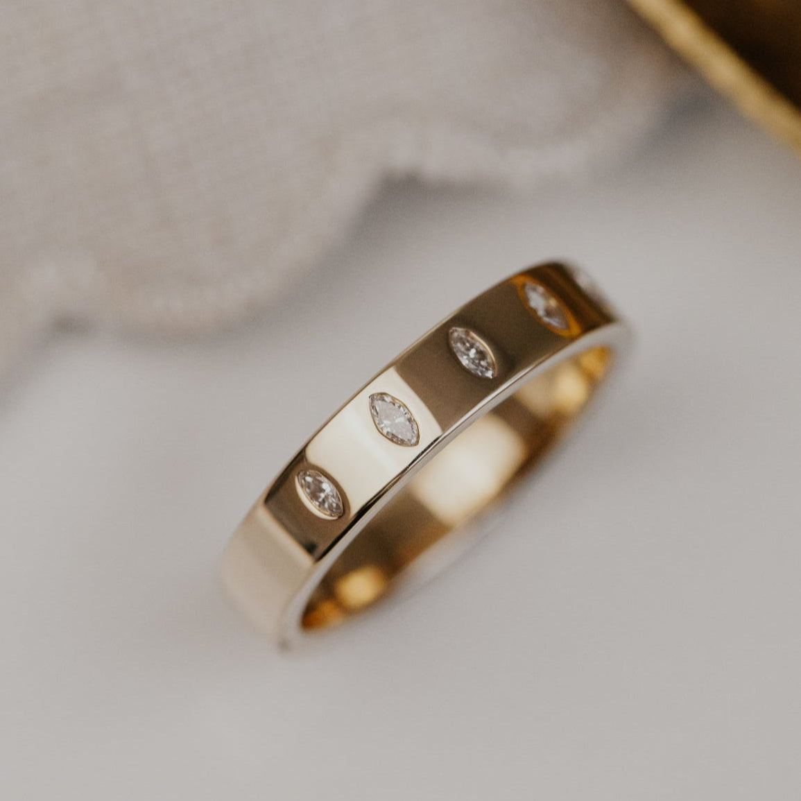 Gold wedding band with marquise diamonds on a neutral background