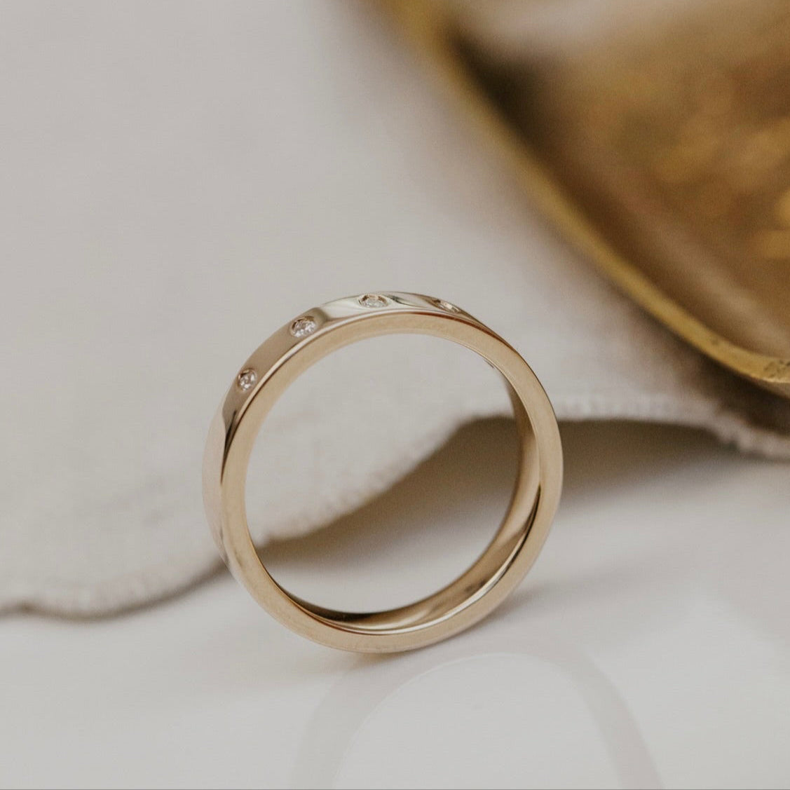 Gold wedding band with small diamonds on a light background