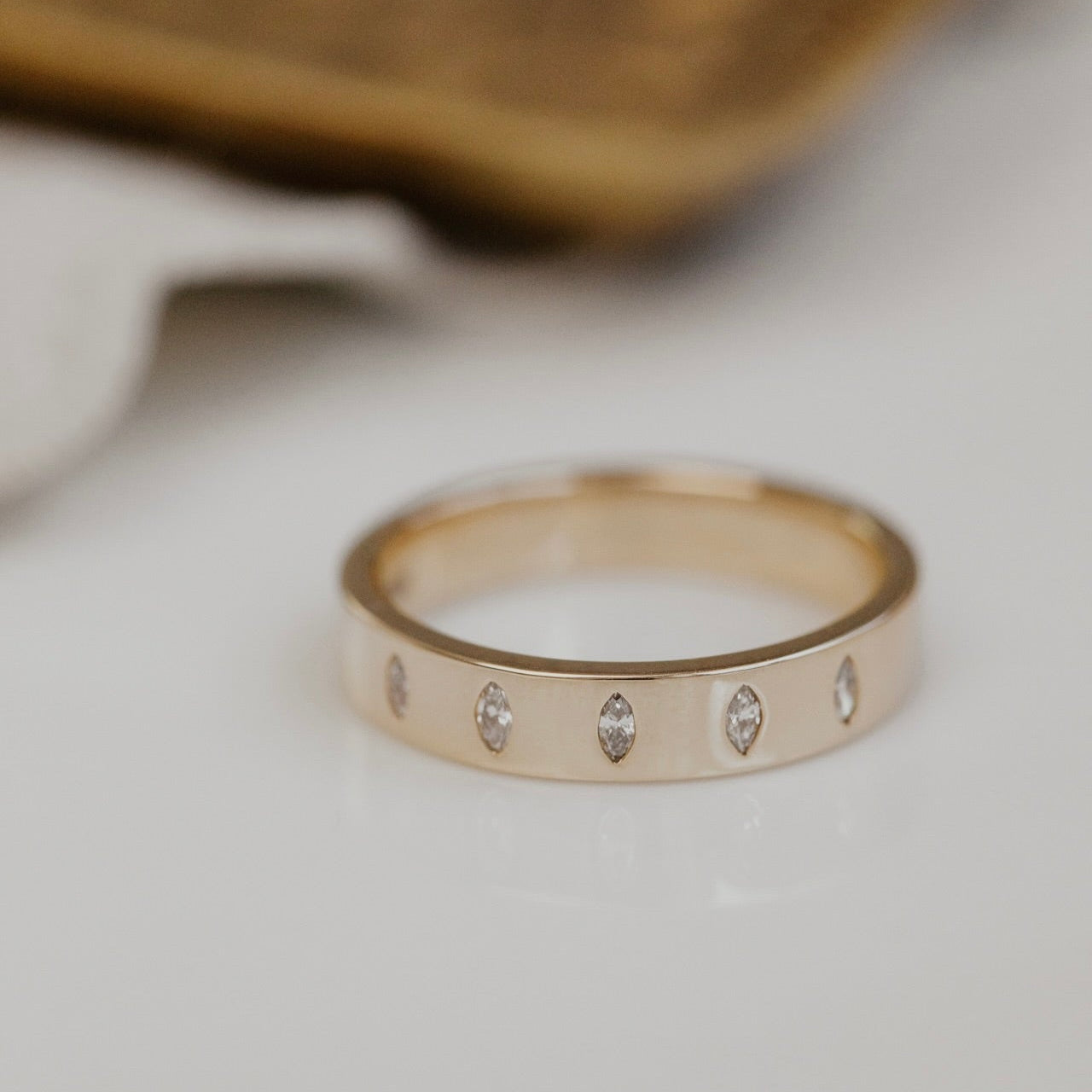 Gold band ring with embedded stones on a light background